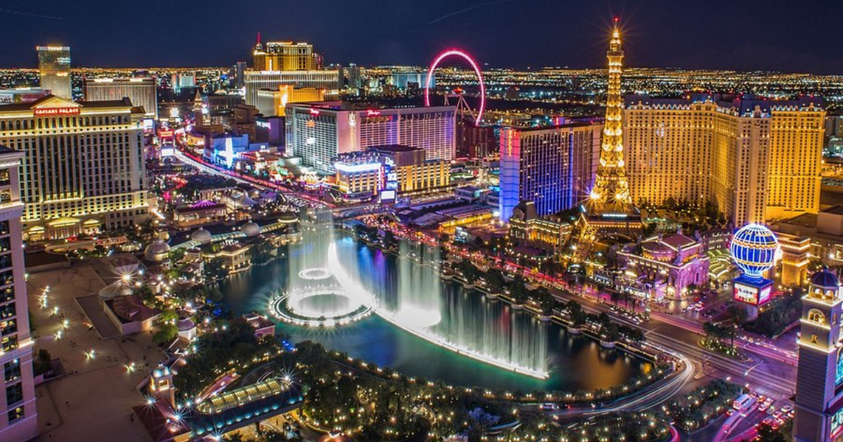 A lively group of friends enjoying a night out on the Las Vegas Strip with neon lights in the background.